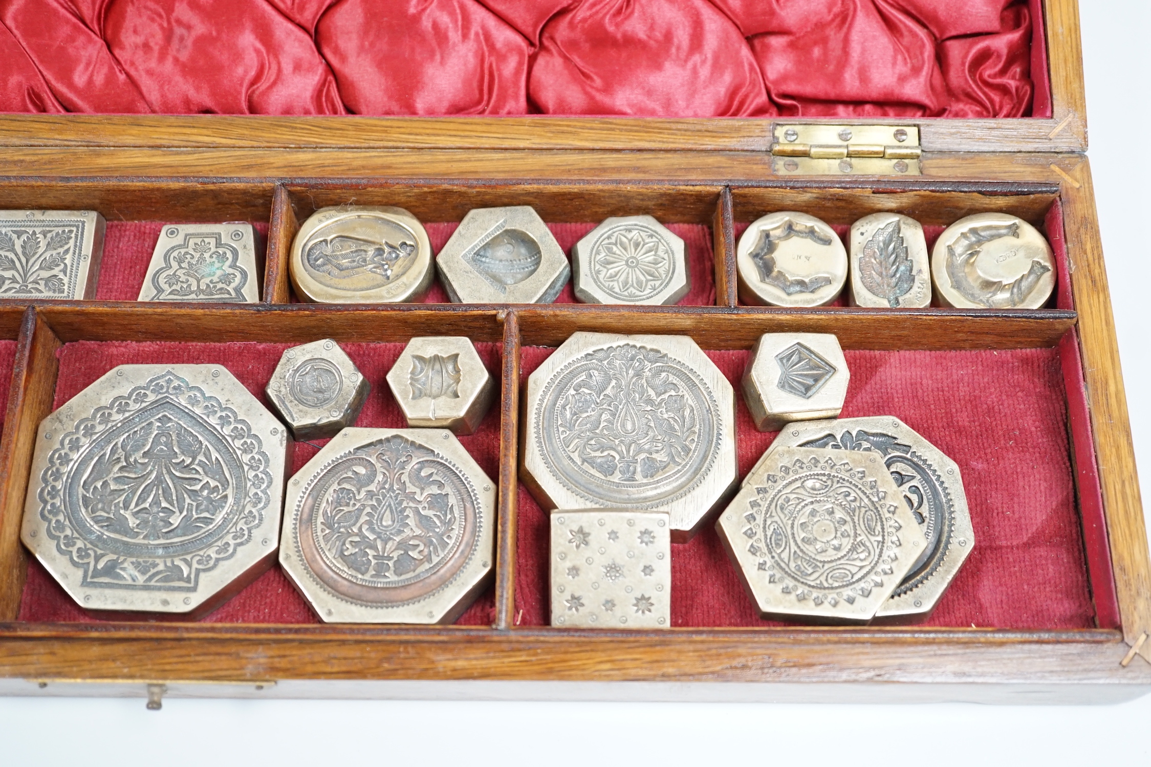 A cased group of Indian or Afghan brass seals or stamps, case 45.5cm wide, 14cm deep